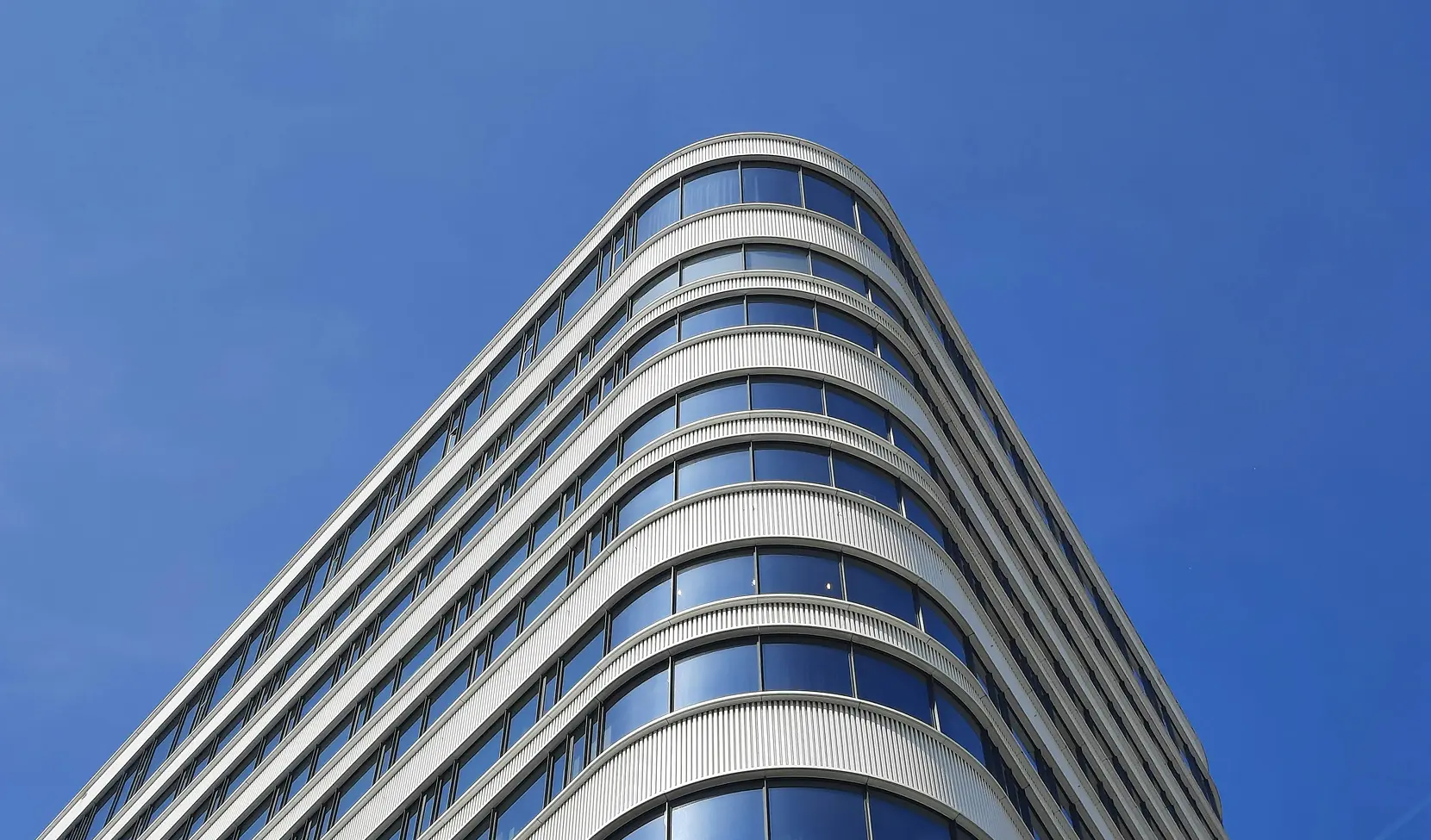 Contemporary building corner with rounded design and blue-tinted windows