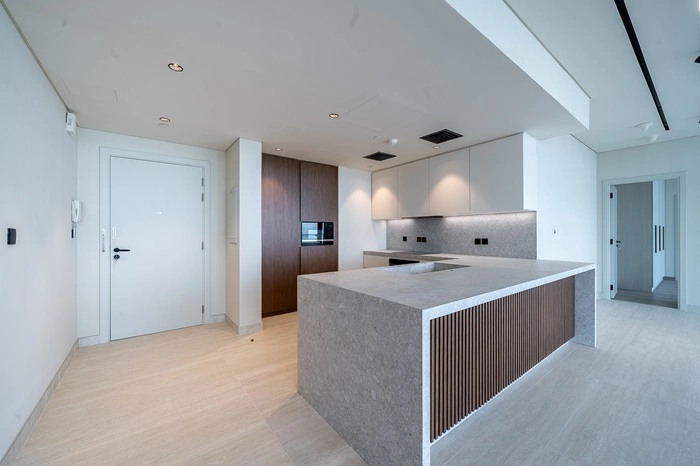 Modern Kitchen with Large Gray Stone Island, Integrated Appliances, and Wood Cabinetry