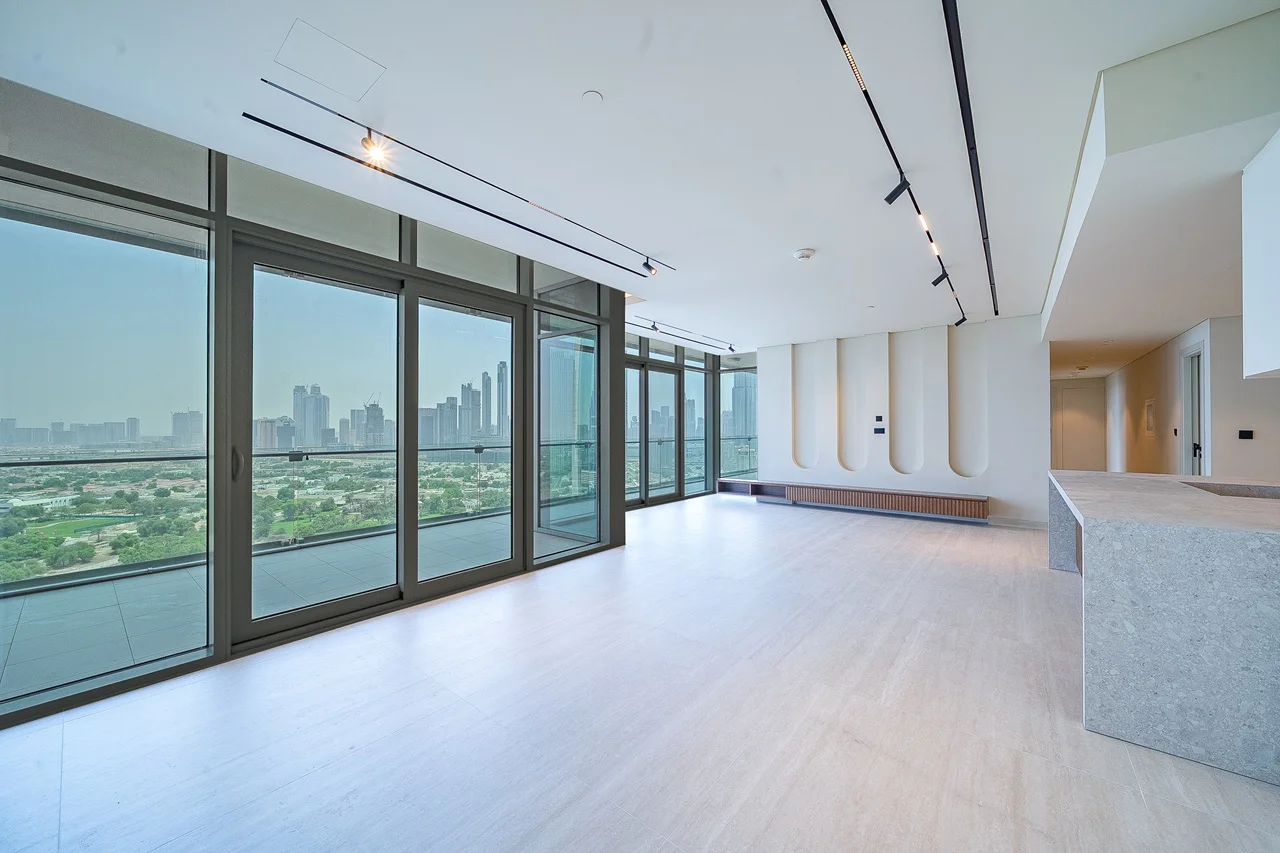 Open-plan living area with panoramic city views through floor-to-ceiling sliding glass doors and minimalist track lighting.