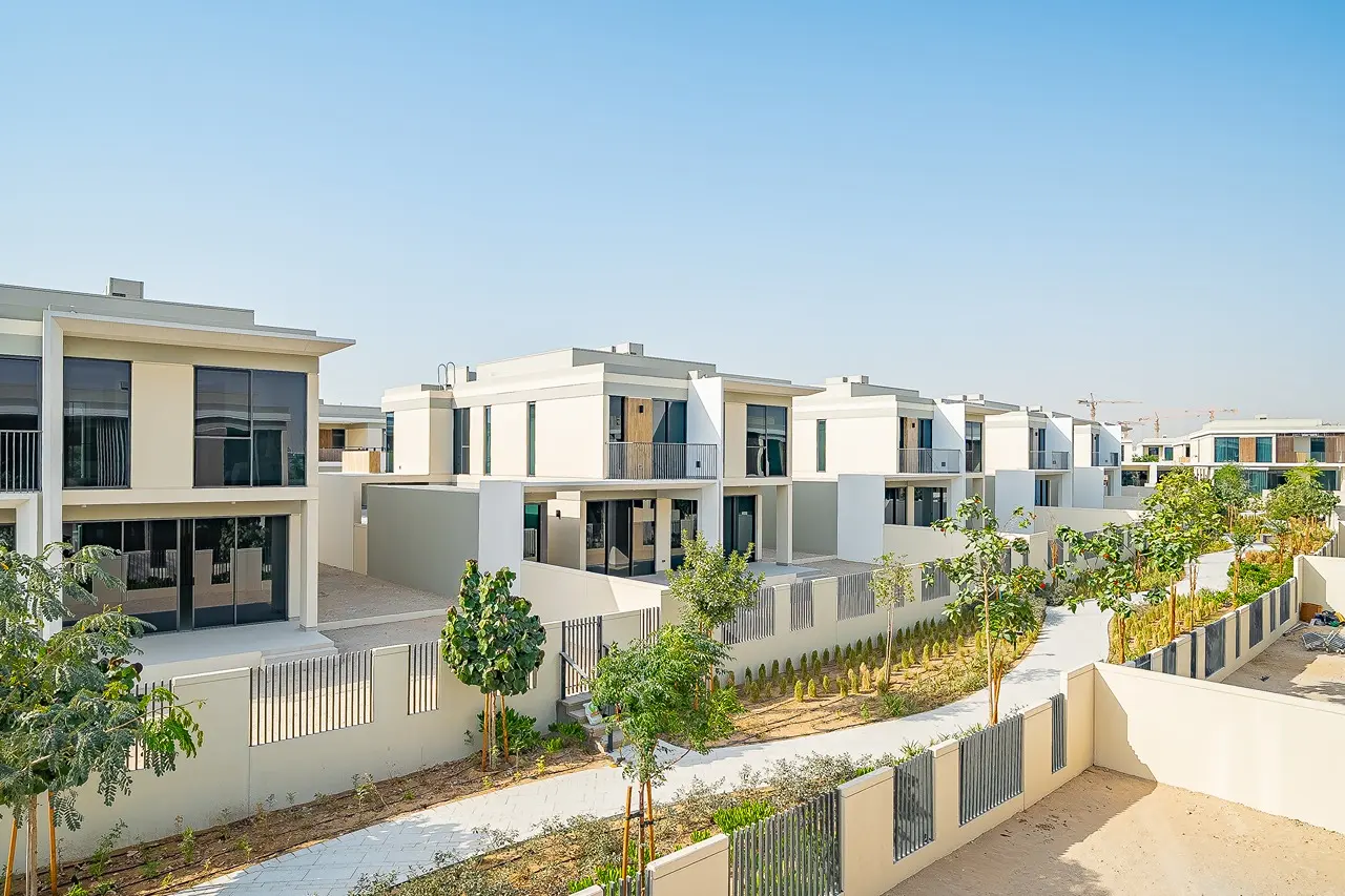 Row of Modern Townhouses with minimalist white and grey facades and upper balconies in a residential development.